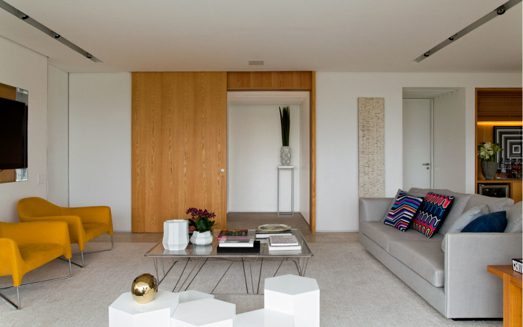 Imagem de forro de gesso enxuto e sem rodapés. O apê conquistou visual limpo, como se as paredes flutuassem. Marcenaria em tom mel – carvalho americano – entrou em cena para desbancar a frieza.