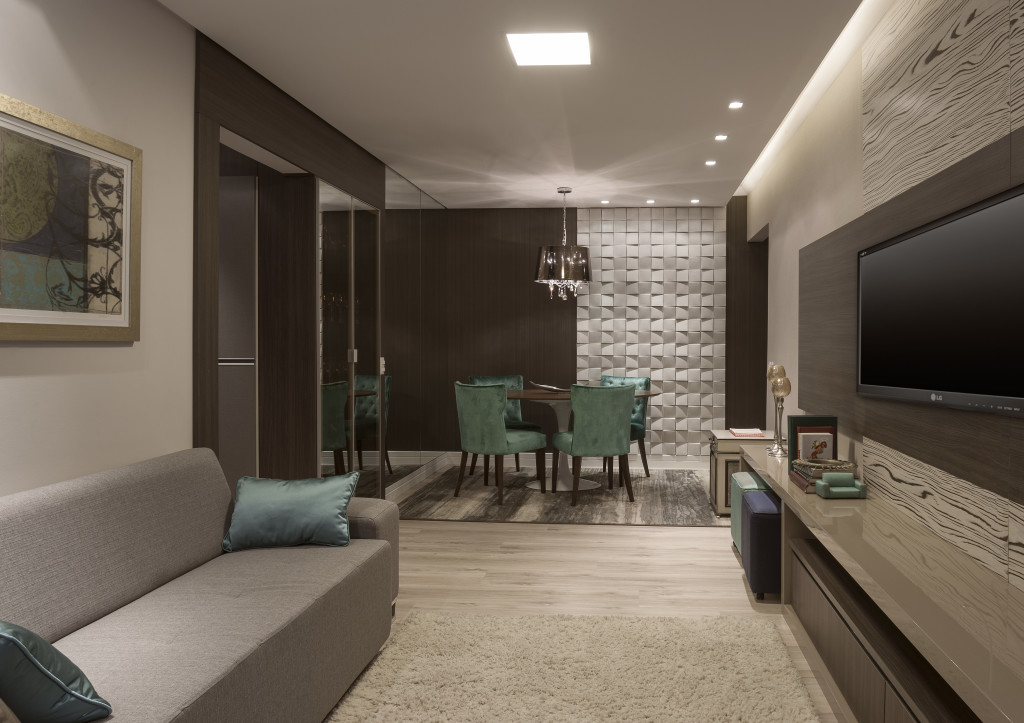 Imagem da bancada de estudos que divide o quarto e o closet. O painel turquesa organiza o espaço e ainda embute a televisão.