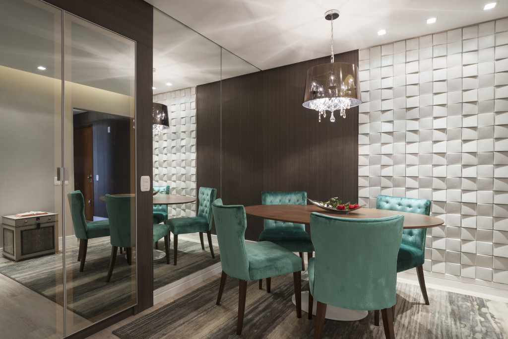 Imagem de painel amadeirado e parede revestida de pedra cimentícia com relevo na sala de jantar integrada.